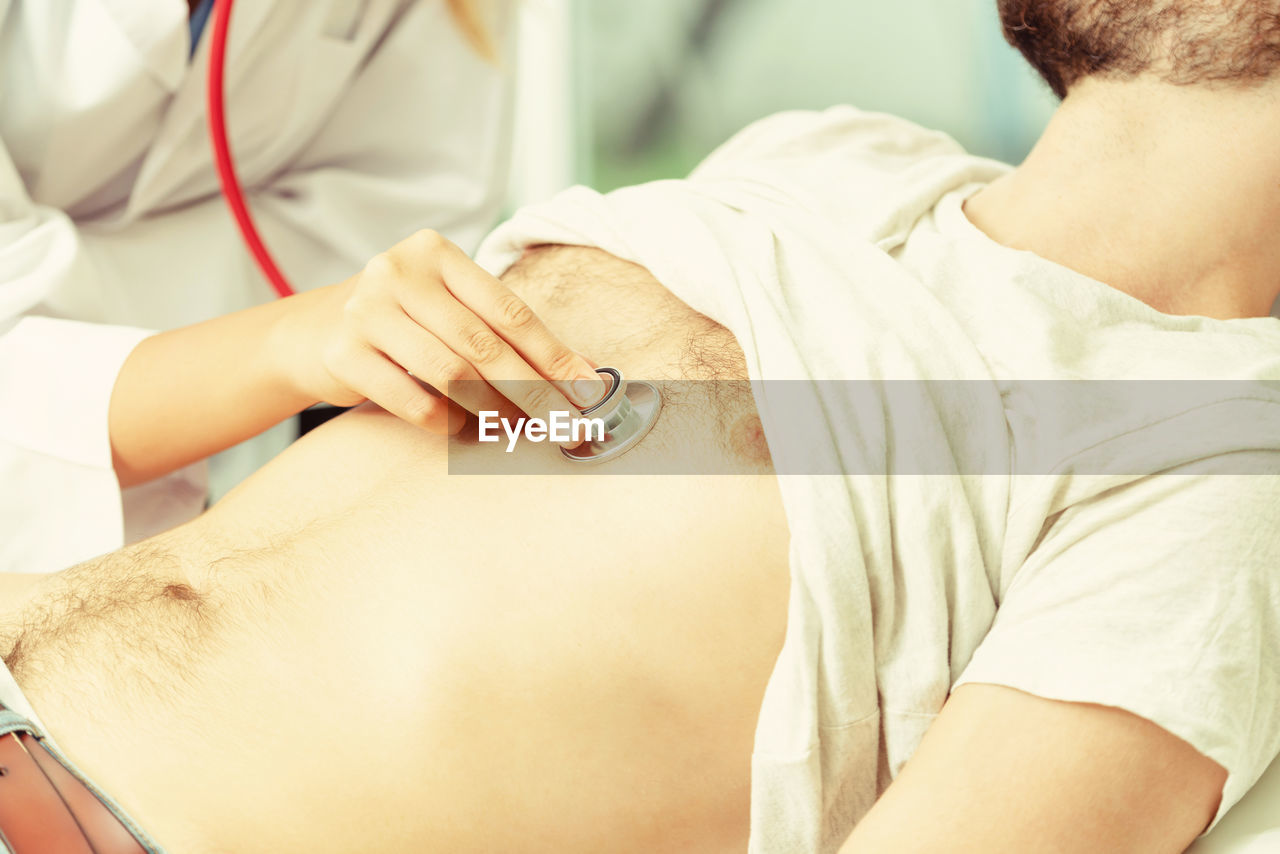 Midsection of female doctor examining patient chest at clinic