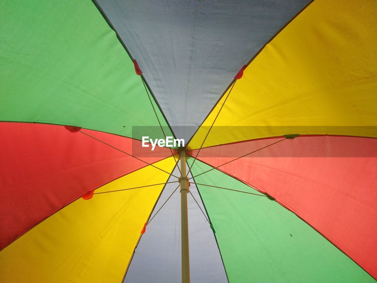LOW ANGLE VIEW OF MULTI COLORED UMBRELLA AGAINST YELLOW WALL