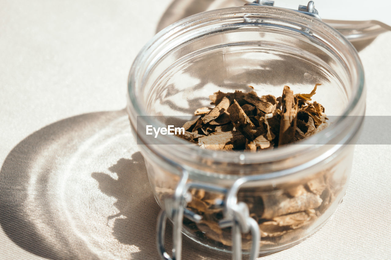 High angle view of iboga roots in glass jar on gray background