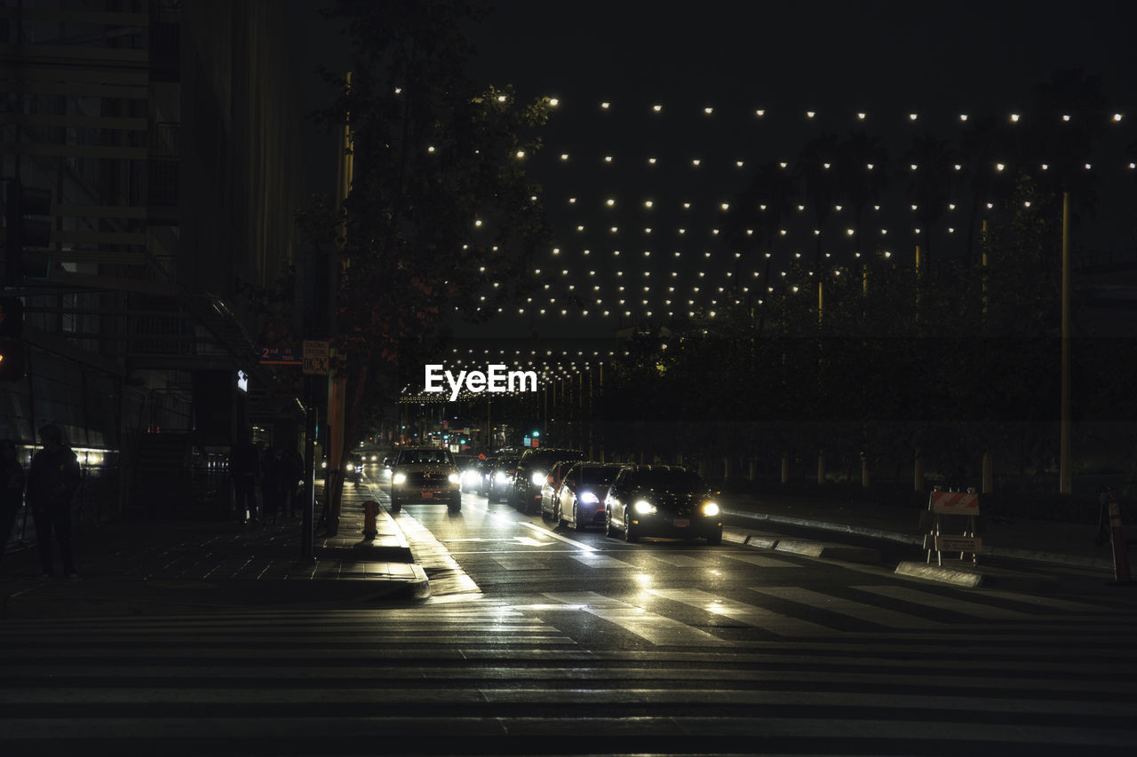 ILLUMINATED STREET AMIDST BUILDINGS AT NIGHT