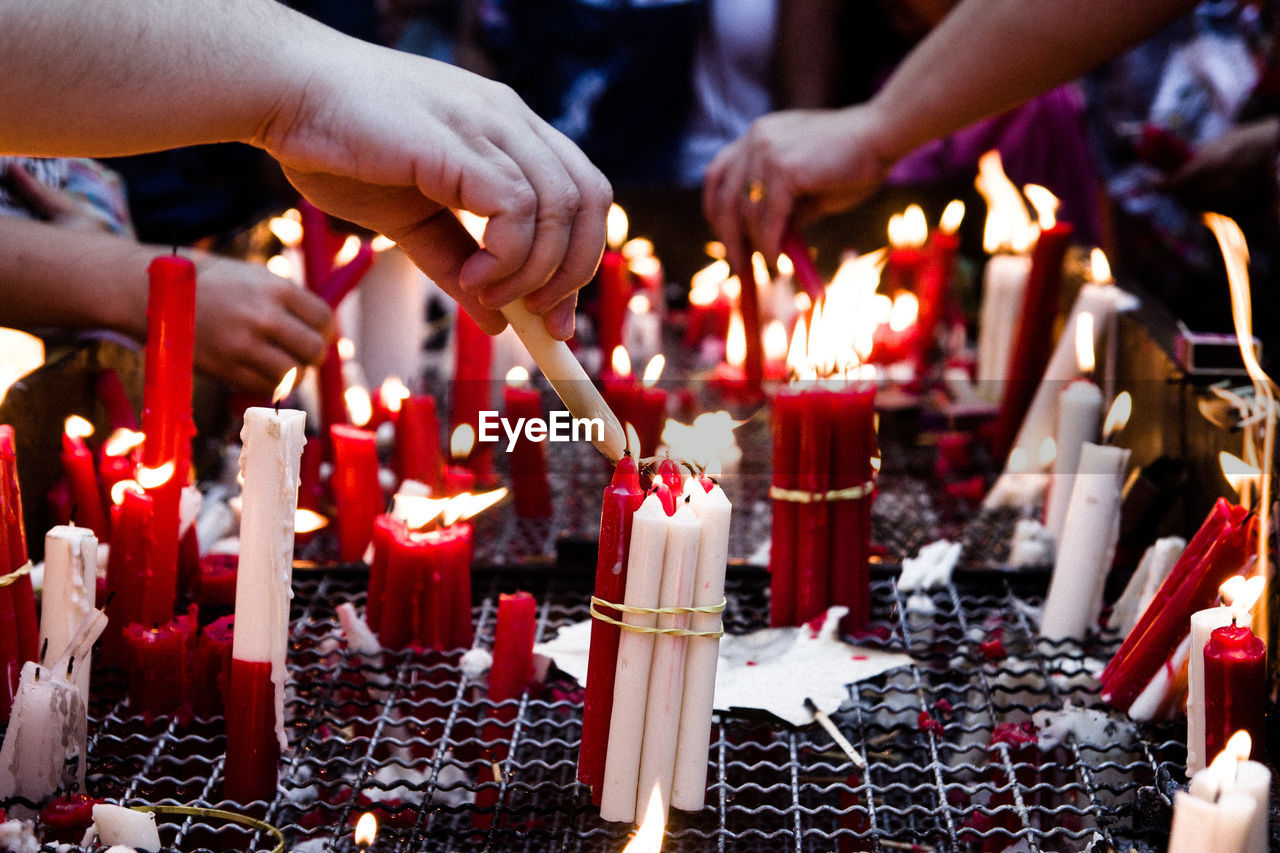 People lighting bunch of candles