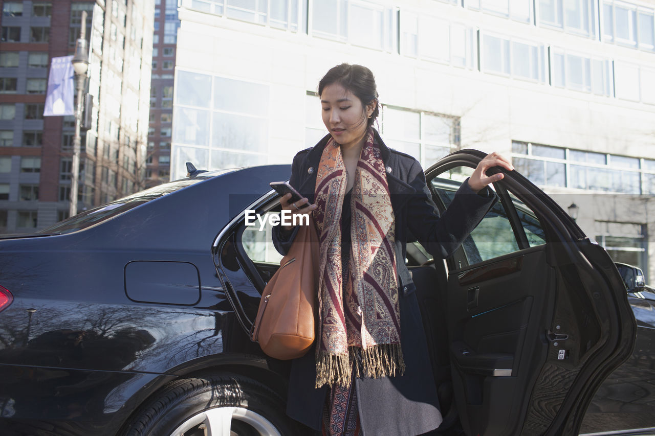 Young asian businesswoman getting out of car service limousine