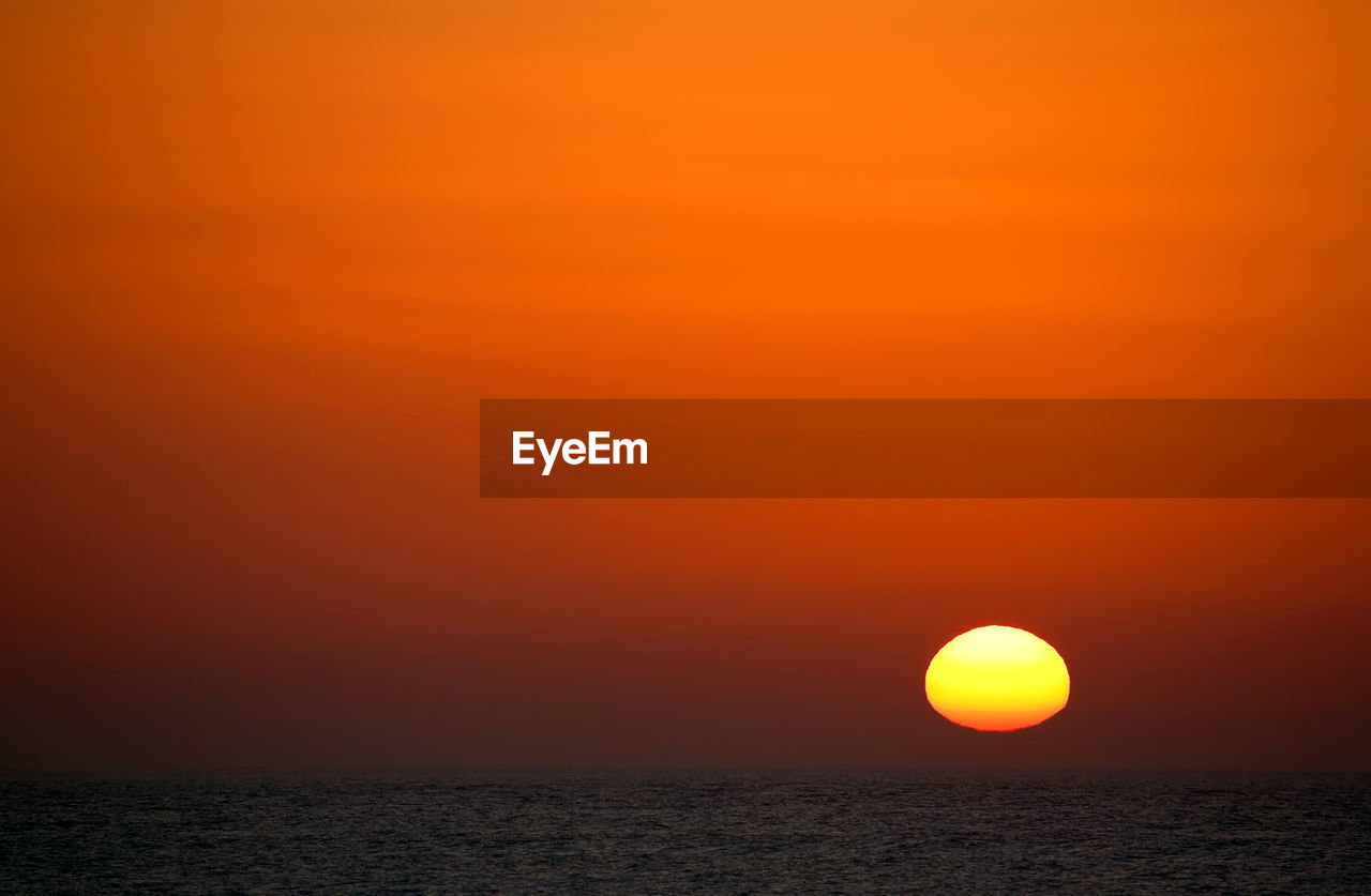 SCENIC VIEW OF SEA AGAINST ORANGE SKY DURING SUNSET