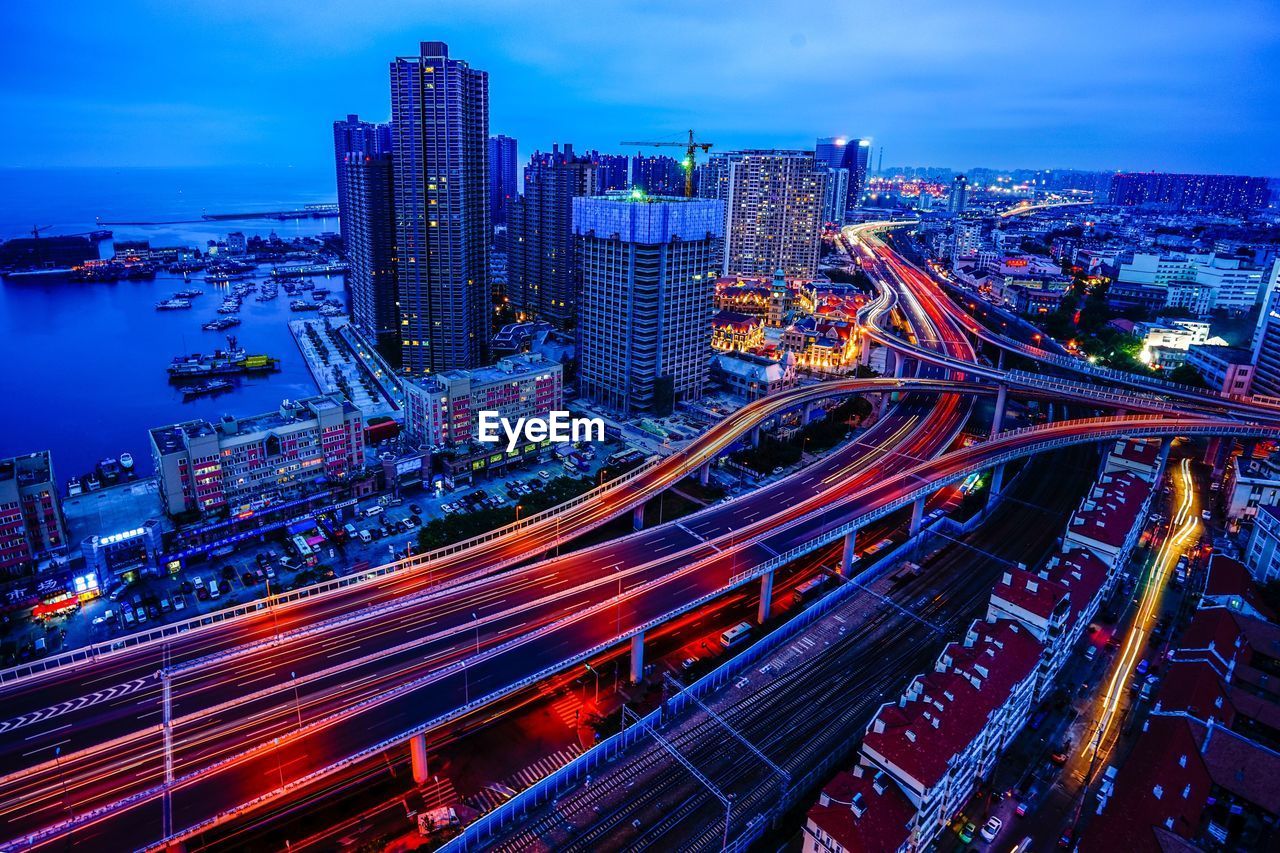 Aerial view of light trails on multiple lane highways in city at dusk