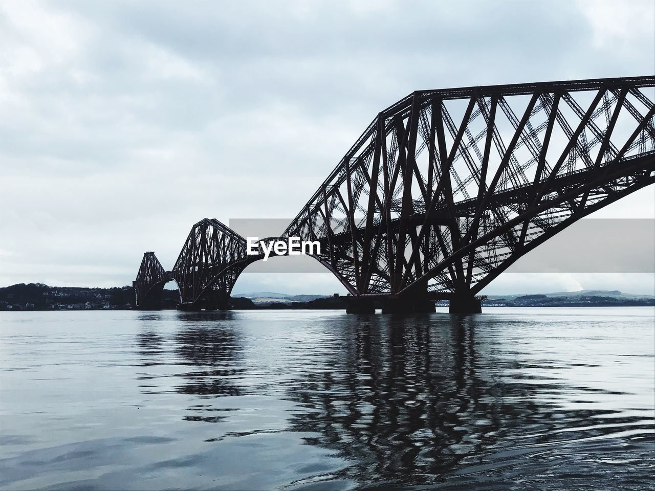 Bridge over river against cloudy sky