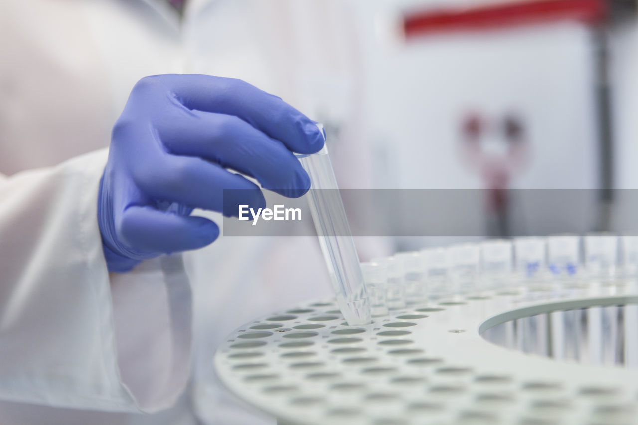 Close-up of human hand holding test tube over rack in laboratory