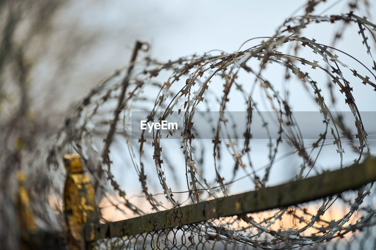 Close-up of barbed wire fence against sky