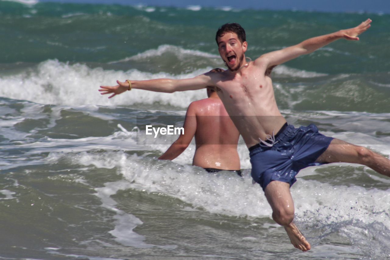 FULL LENGTH OF SHIRTLESS MAN AT SEA