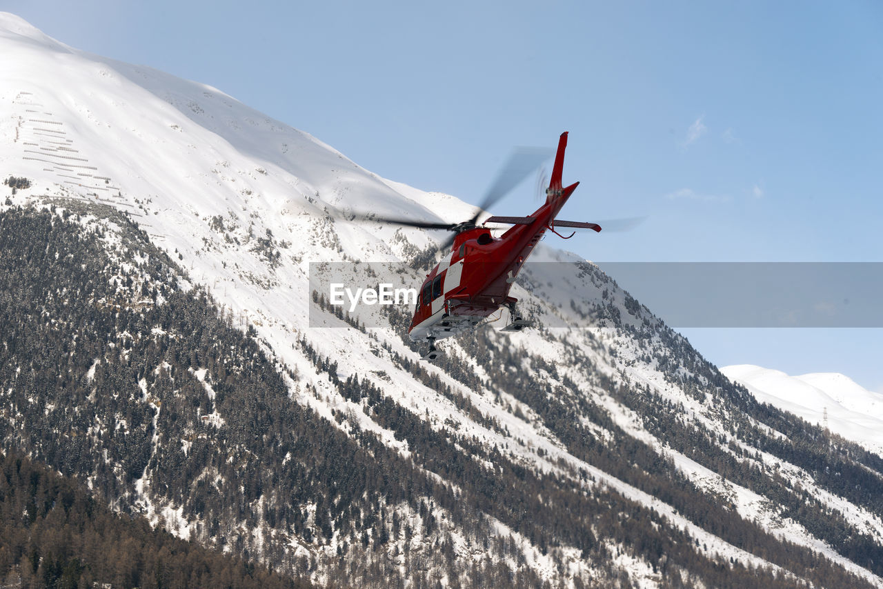 Low angle view of air vehicle by snowcapped mountains against sky