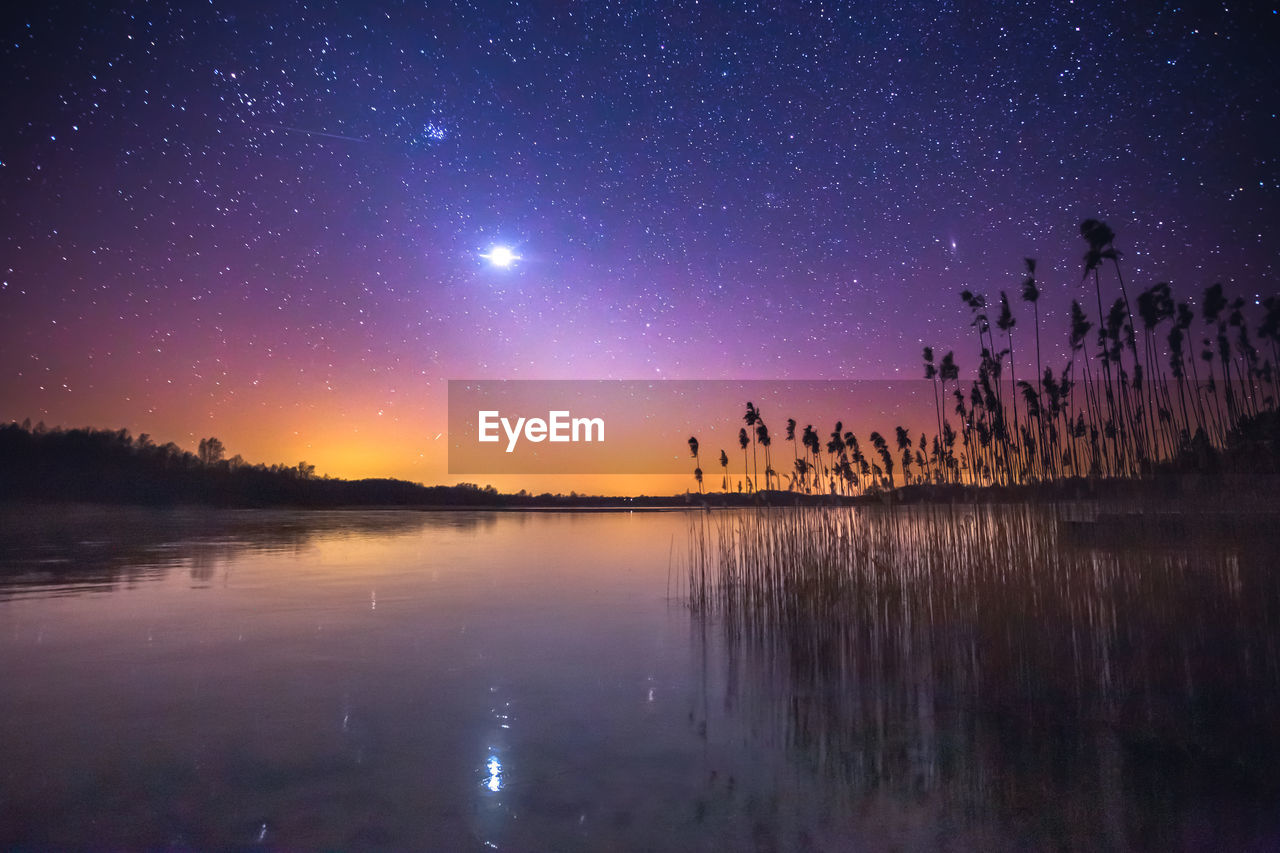 Scenic view of lake against sky at night