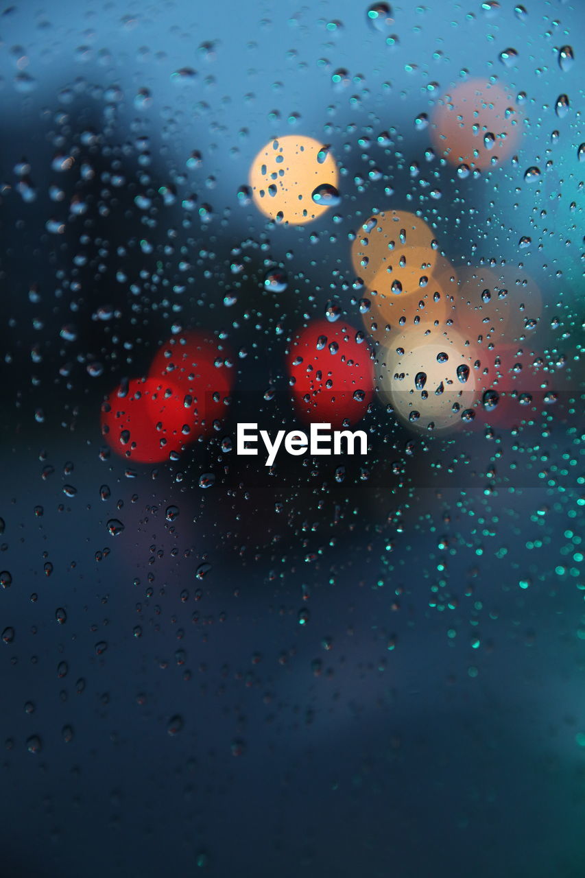 Close-up of raindrops on car window at dusk