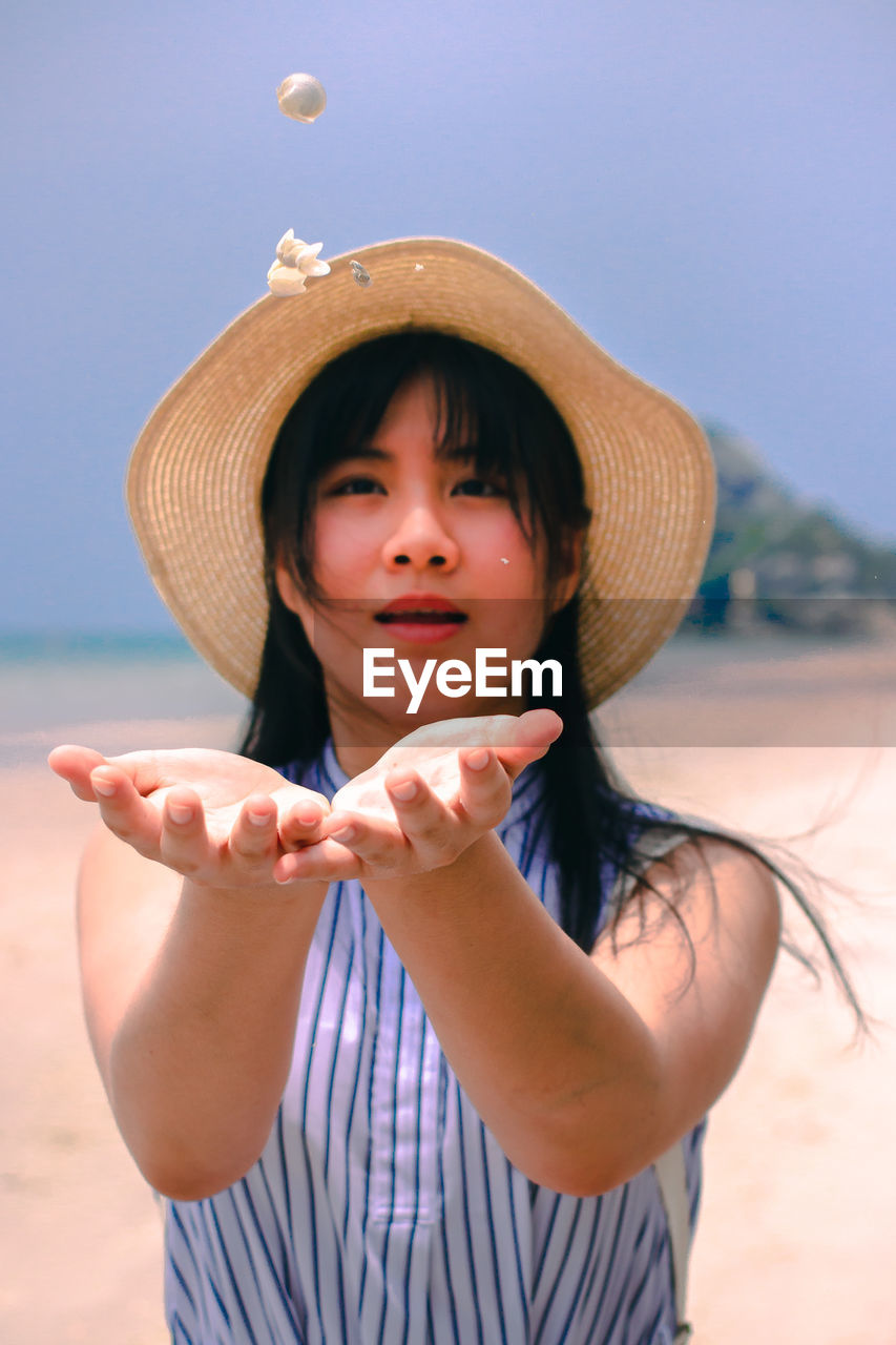 Young woman catching seashells while standing at beach