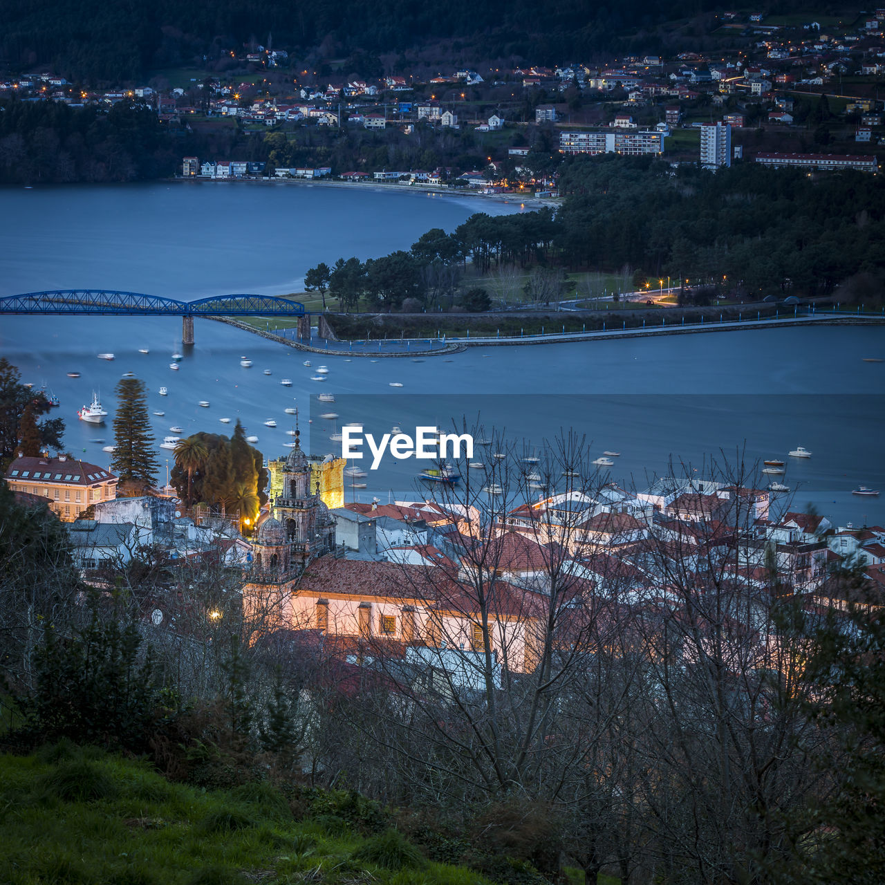 HIGH ANGLE VIEW OF ILLUMINATED BUILDINGS AND RIVER AT NIGHT