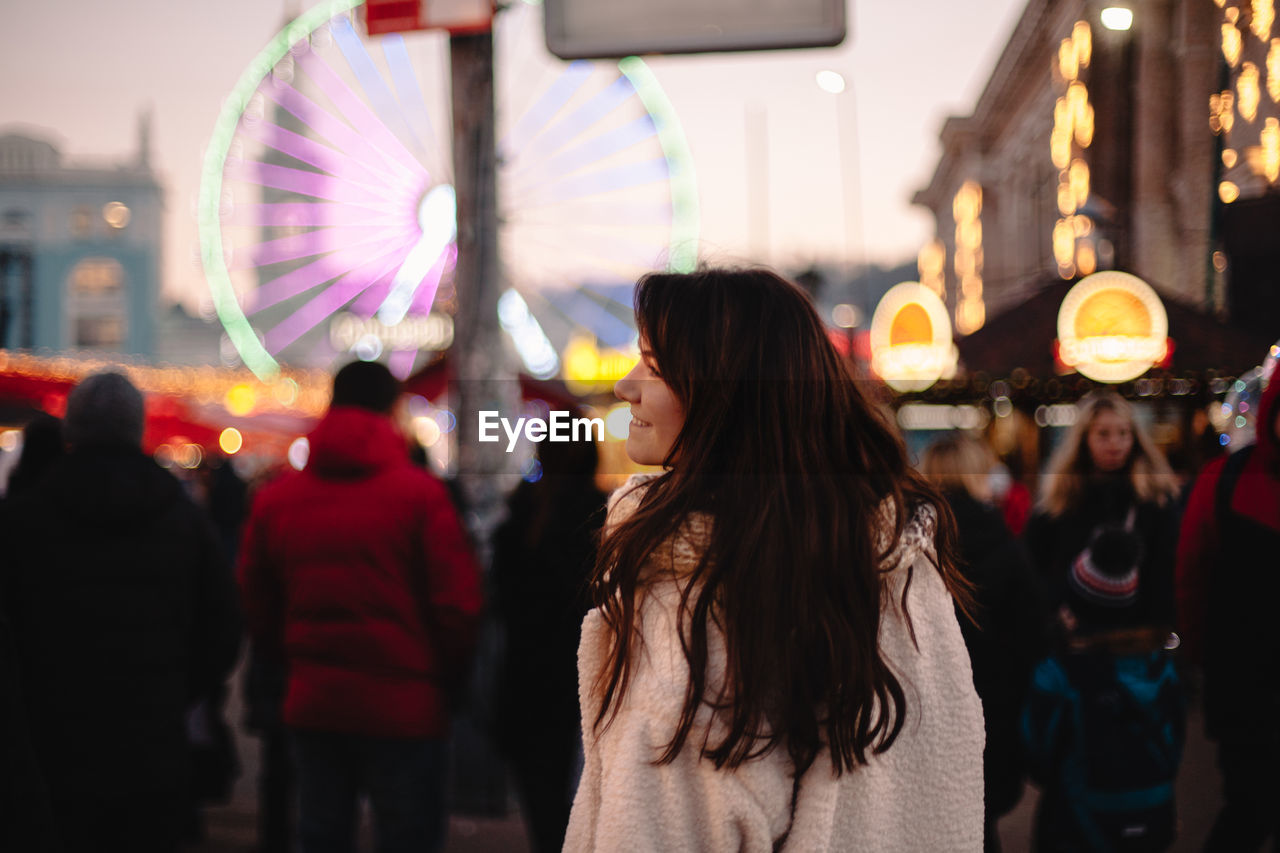 Happy teenage girl walking in christmas market in evening city