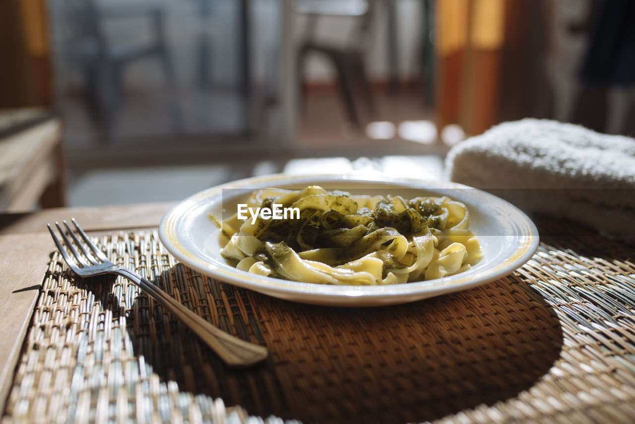 Plate of pasta with pesto sauce with natural light through the window.
