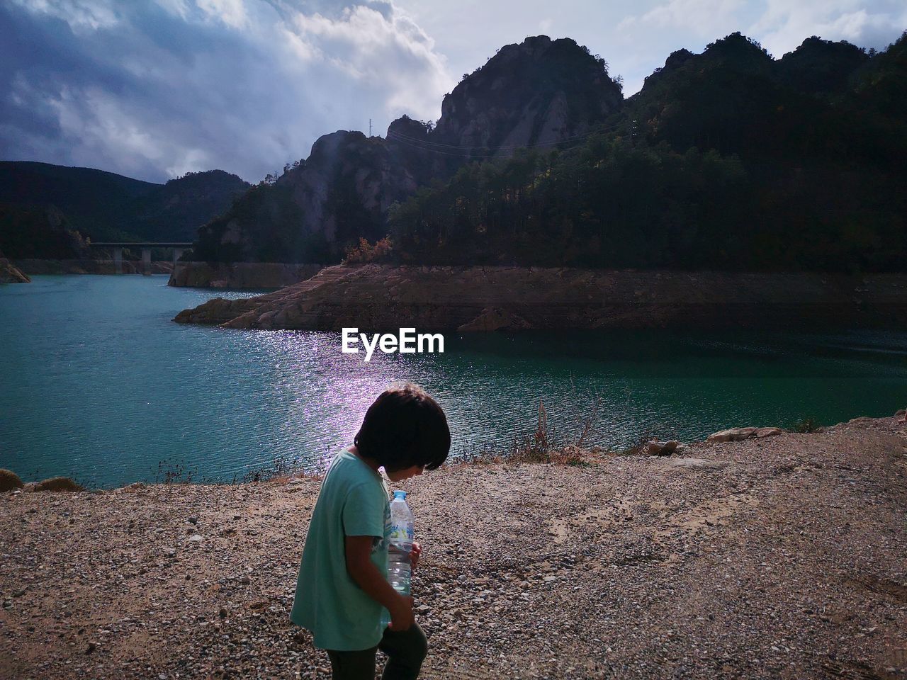 Rear view of boy looking at lake against mountain