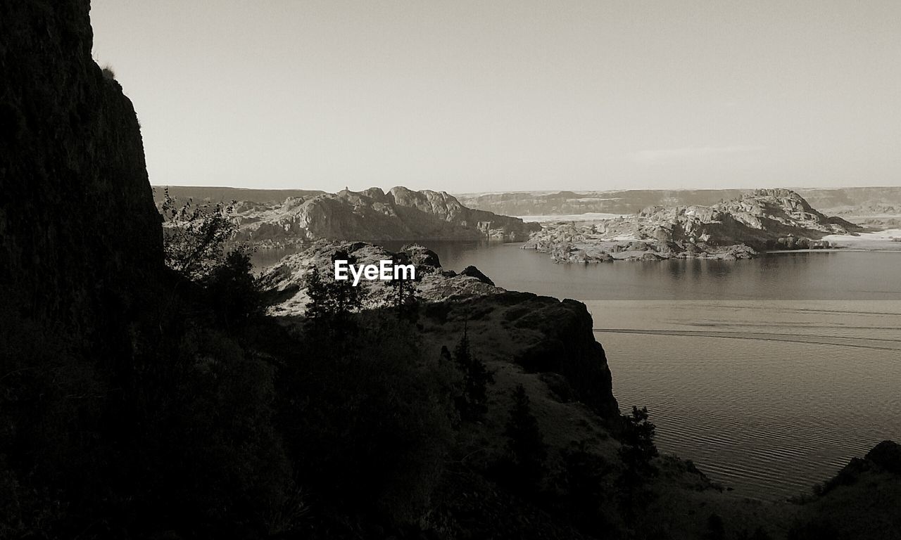 Scenic view of mountain by sea against clear sky