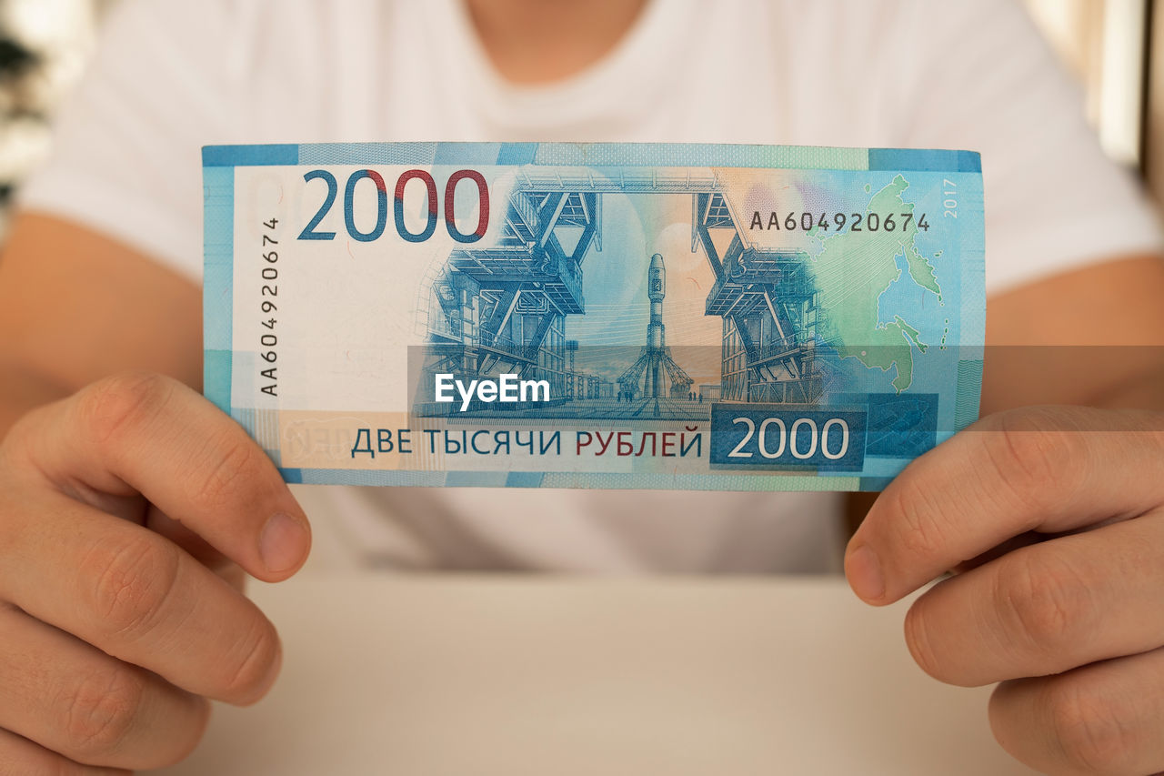 A close-up man holds in his hands an unfolded bill with a face value of 2000 rubles. russian money.