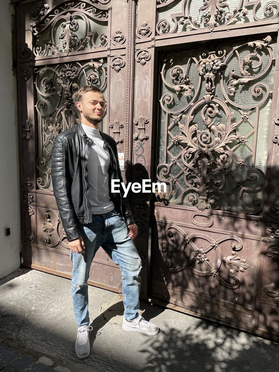 PORTRAIT OF YOUNG MAN STANDING AT ENTRANCE OF