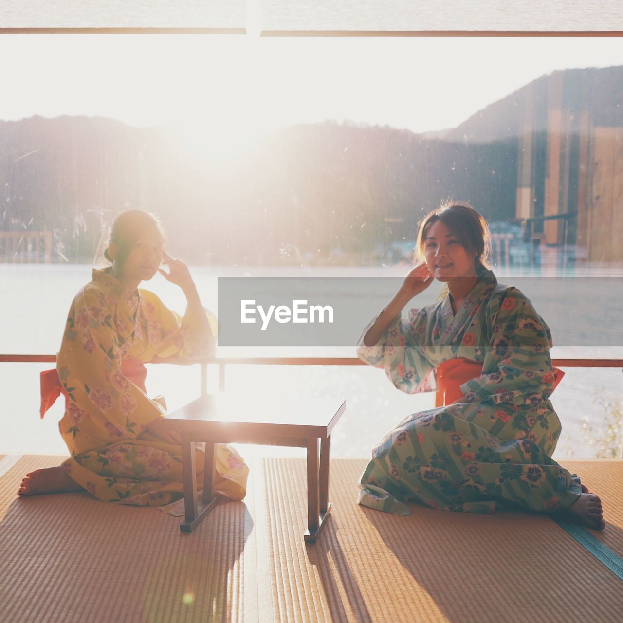 Young women wearing kimonos sitting by window 
