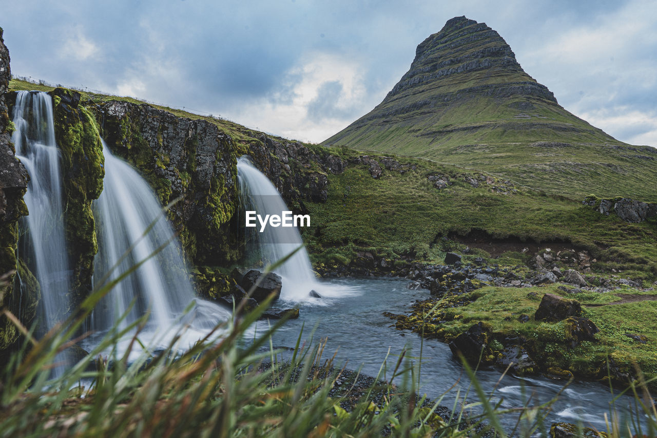 Scenic view of waterfall against mountain kirkjufell