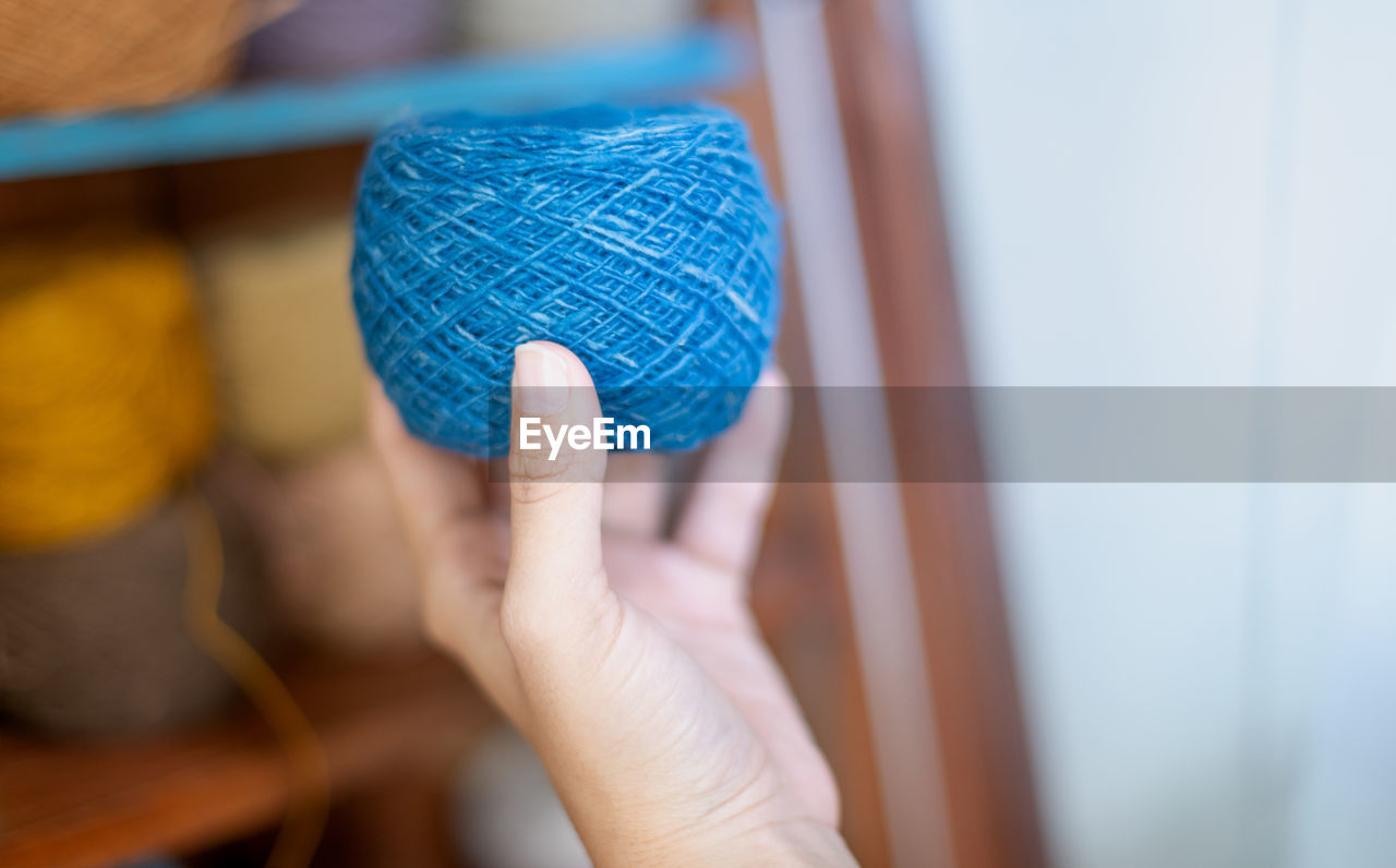 CLOSE-UP OF HAND HOLDING BLUE PAPER WITH TATTOO