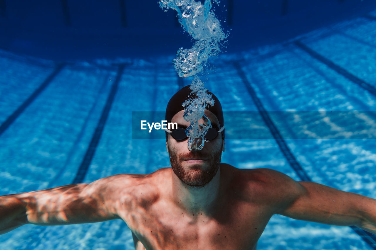 Professional young male swimmer swimming underwater