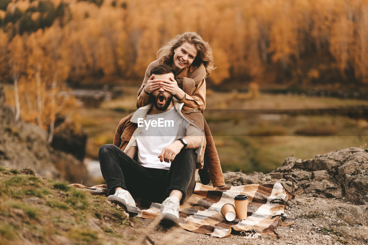 A happy couple in love a man and a woman are traveling walking hiking in the autumn forest in nature