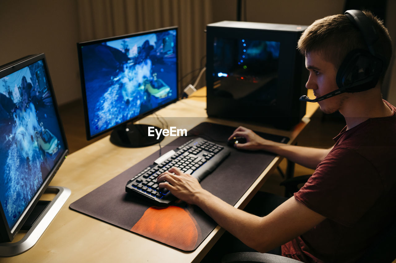 Young man playing video games with computer at desk