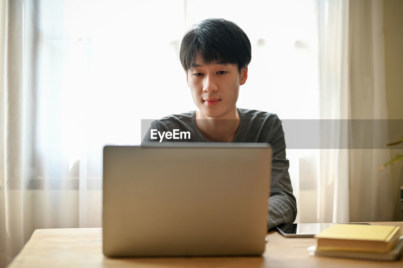 young woman using laptop while sitting at home