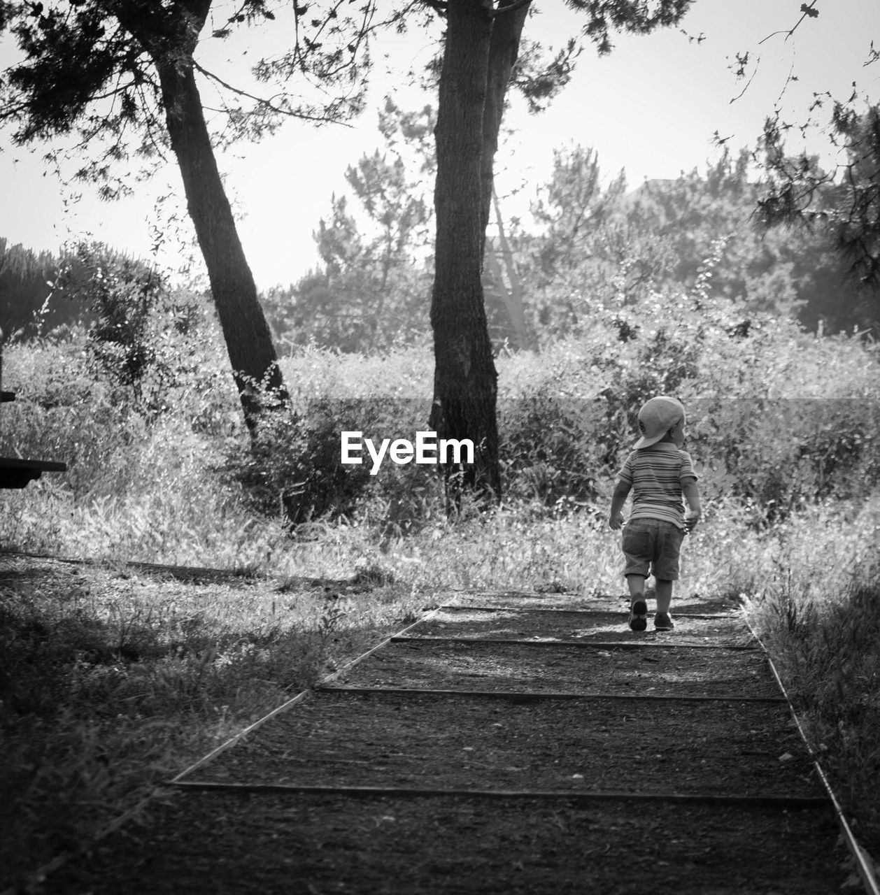 REAR VIEW OF WOMAN WALKING ON FOOTPATH