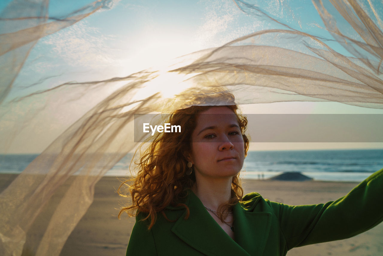 Portrait of woman at beach against sky