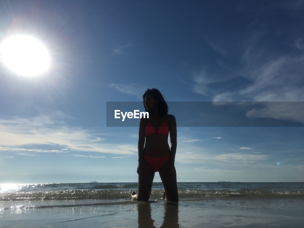 Woman kneeling on shore against sea at beach