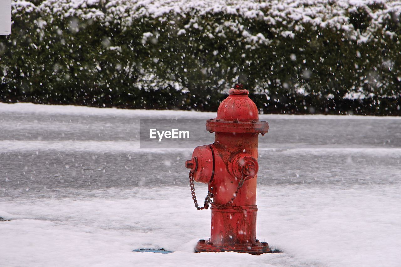 Fire hydrant on snow covered street during snowfall
