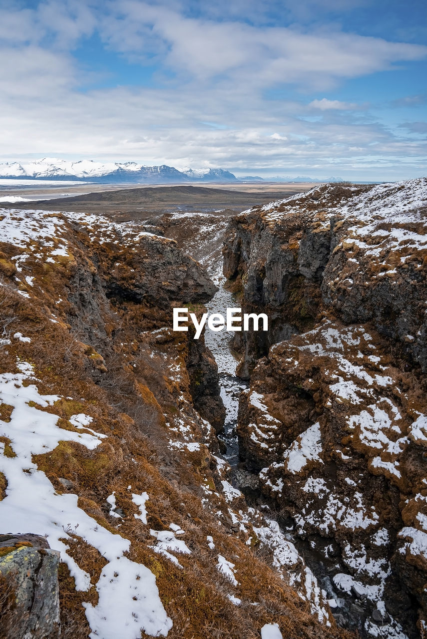 High angle view of snow covered mountains in volcanic valley against sky