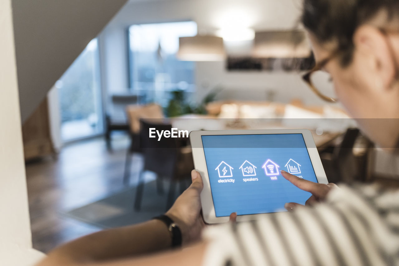 Woman using tablet with smart home control functions at home