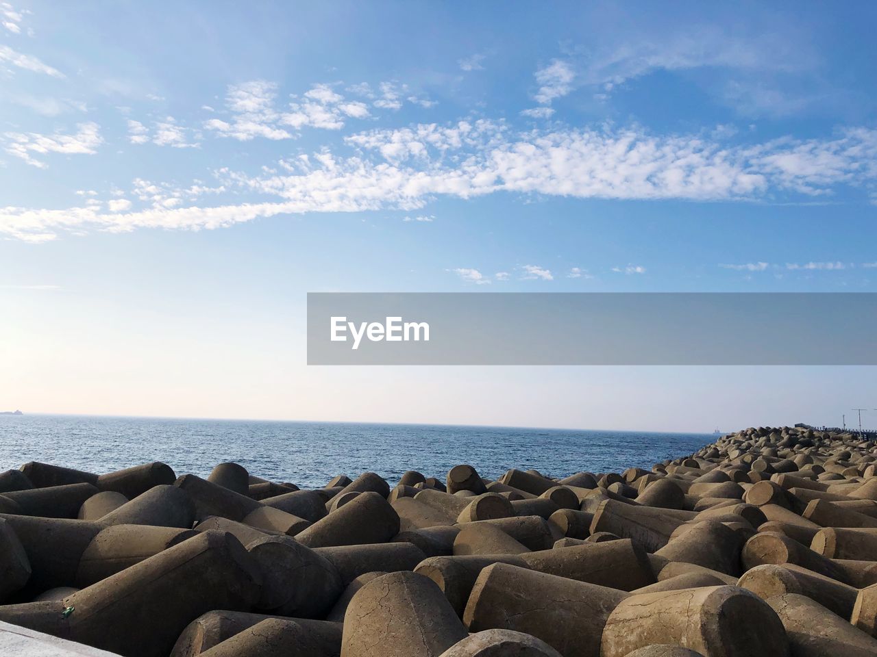 Tetrapods at beach against blue sky