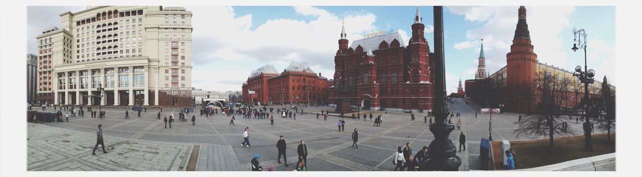 Panoramic shot of buildings with people walking in foreground