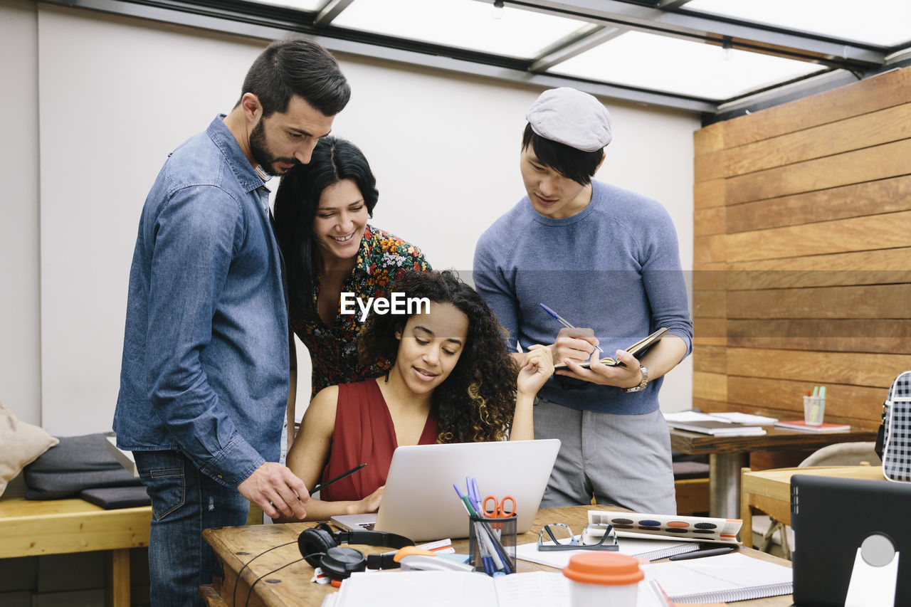 Business people discussing over laptop in office