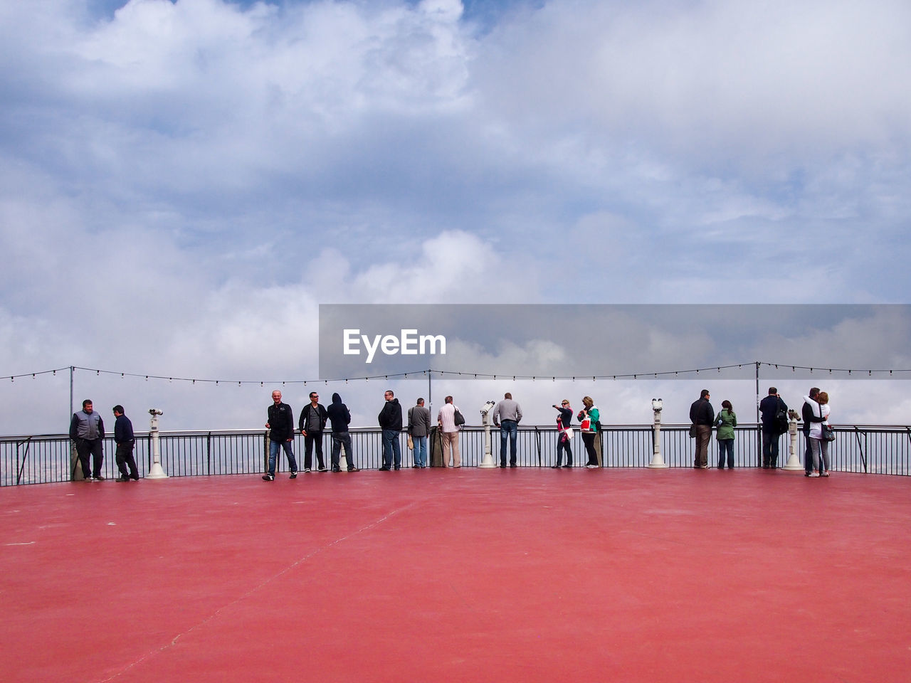 People at observation point against cloudy sky