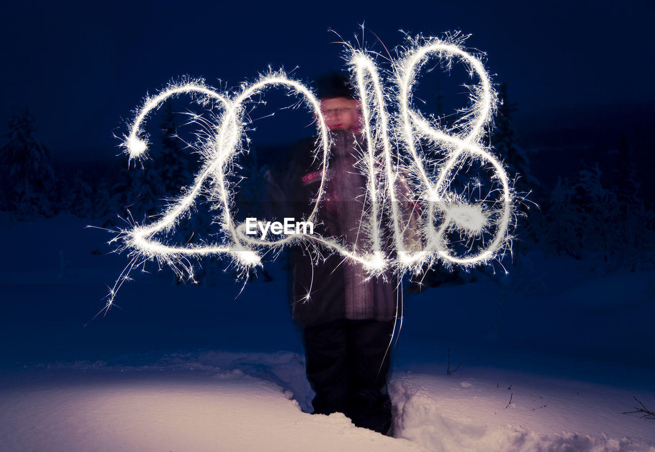 Woman with number fireworks against sky at night