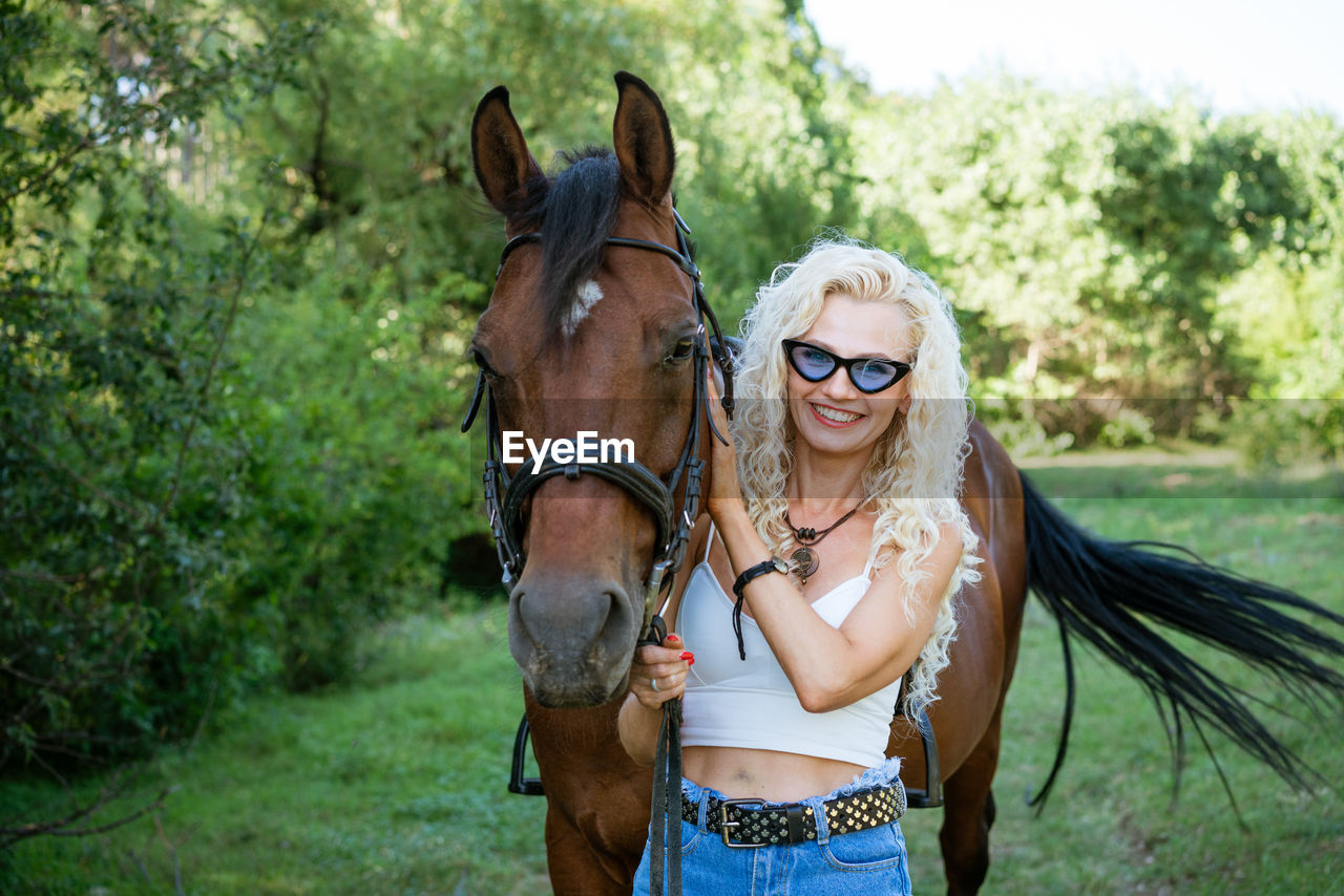 Beautiful woman with horse in summer park