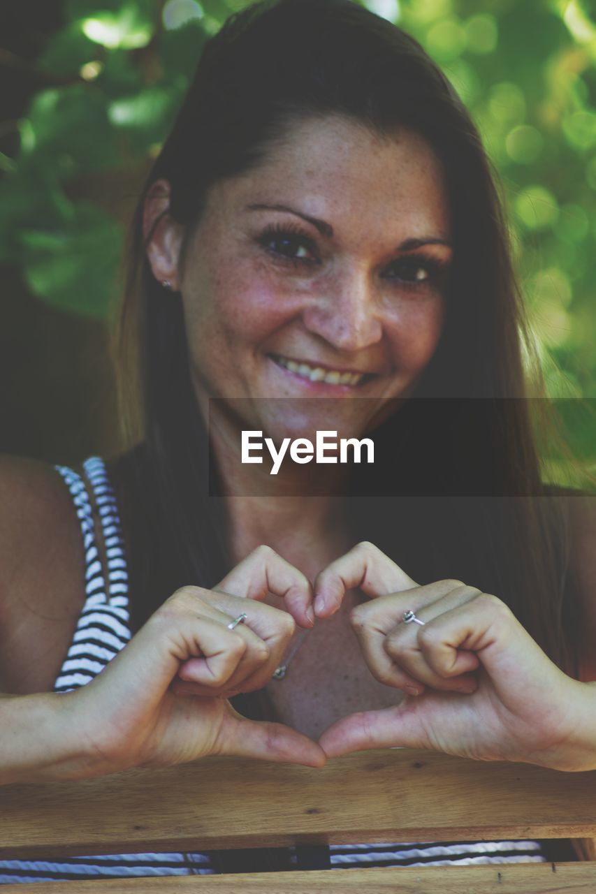 CLOSE-UP PORTRAIT OF A SMILING YOUNG WOMAN WITH HANDS