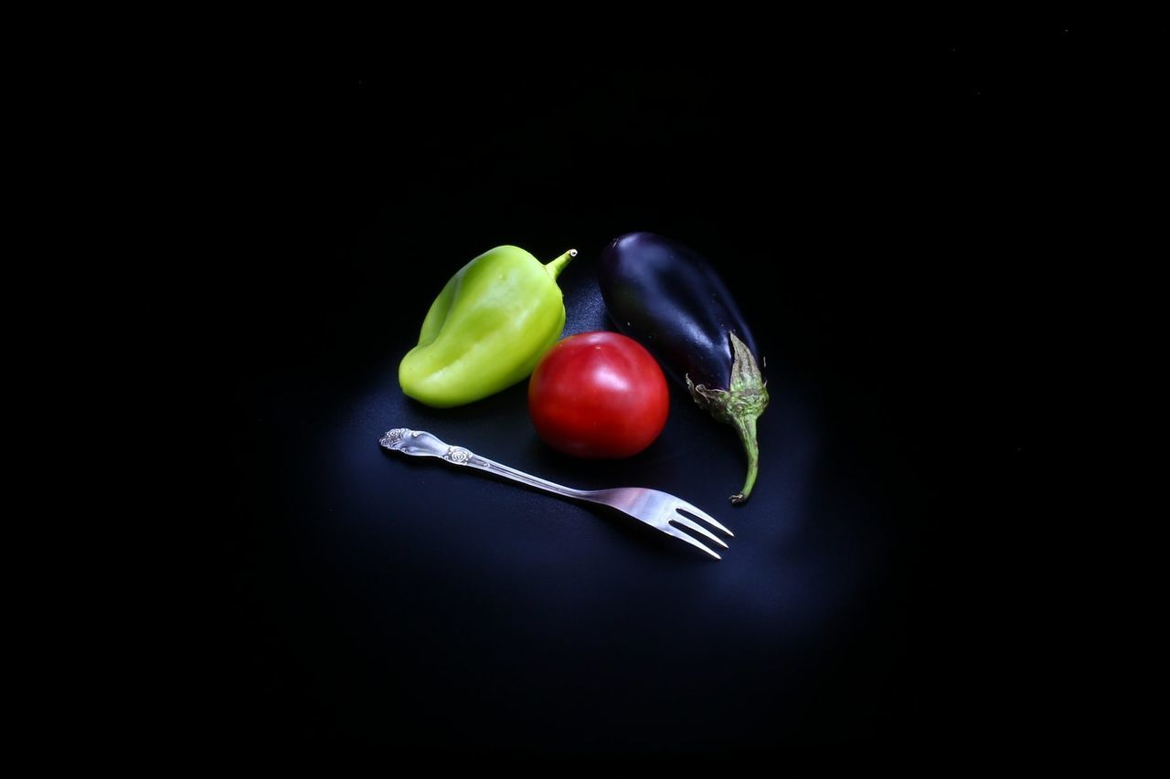 High angle view of vegetables with fork against black background