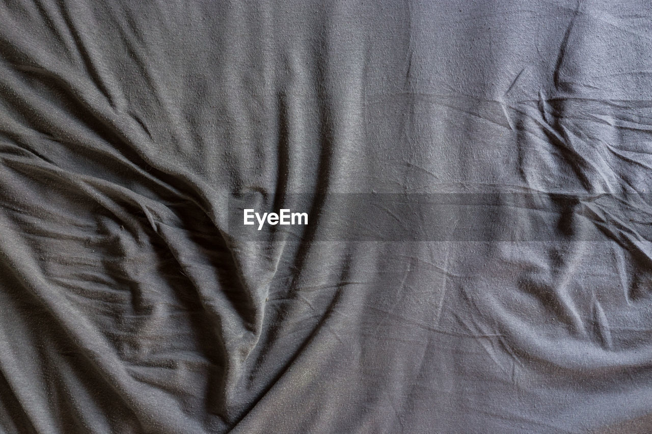 Full frame shot of crumpled gray sheet on bed