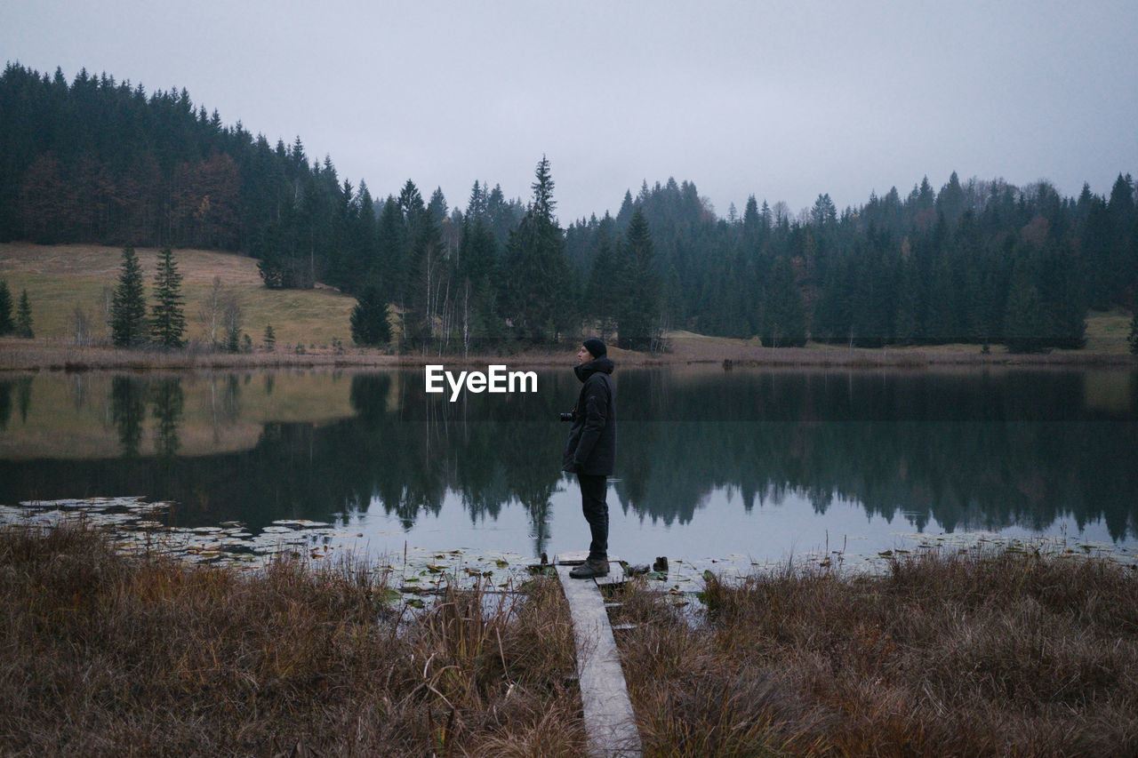 Man standing by lake against sky