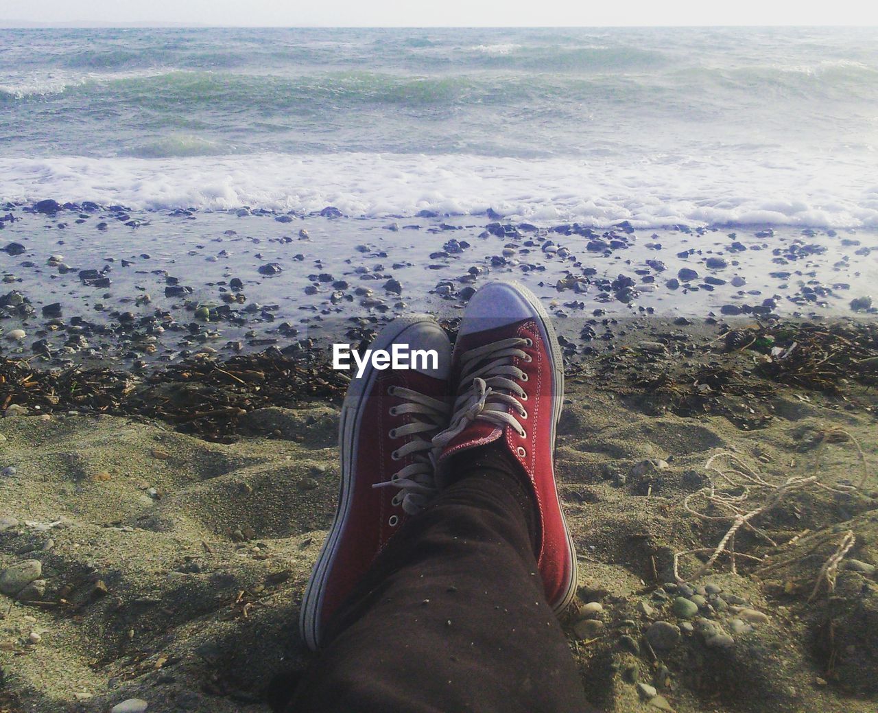 Low section of man on beach against sky