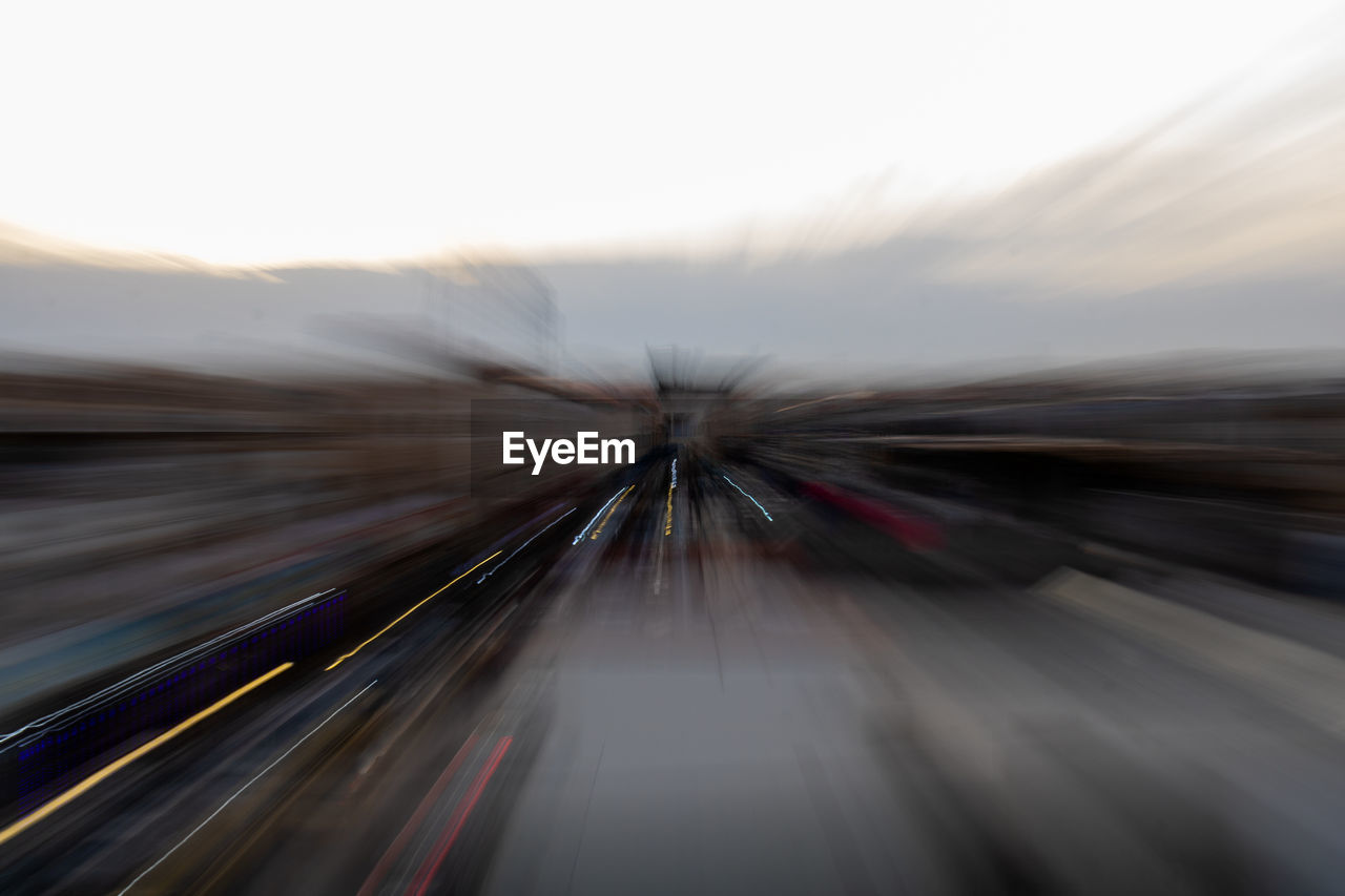 LIGHT TRAILS ON ROAD AGAINST SKY DURING SUNSET