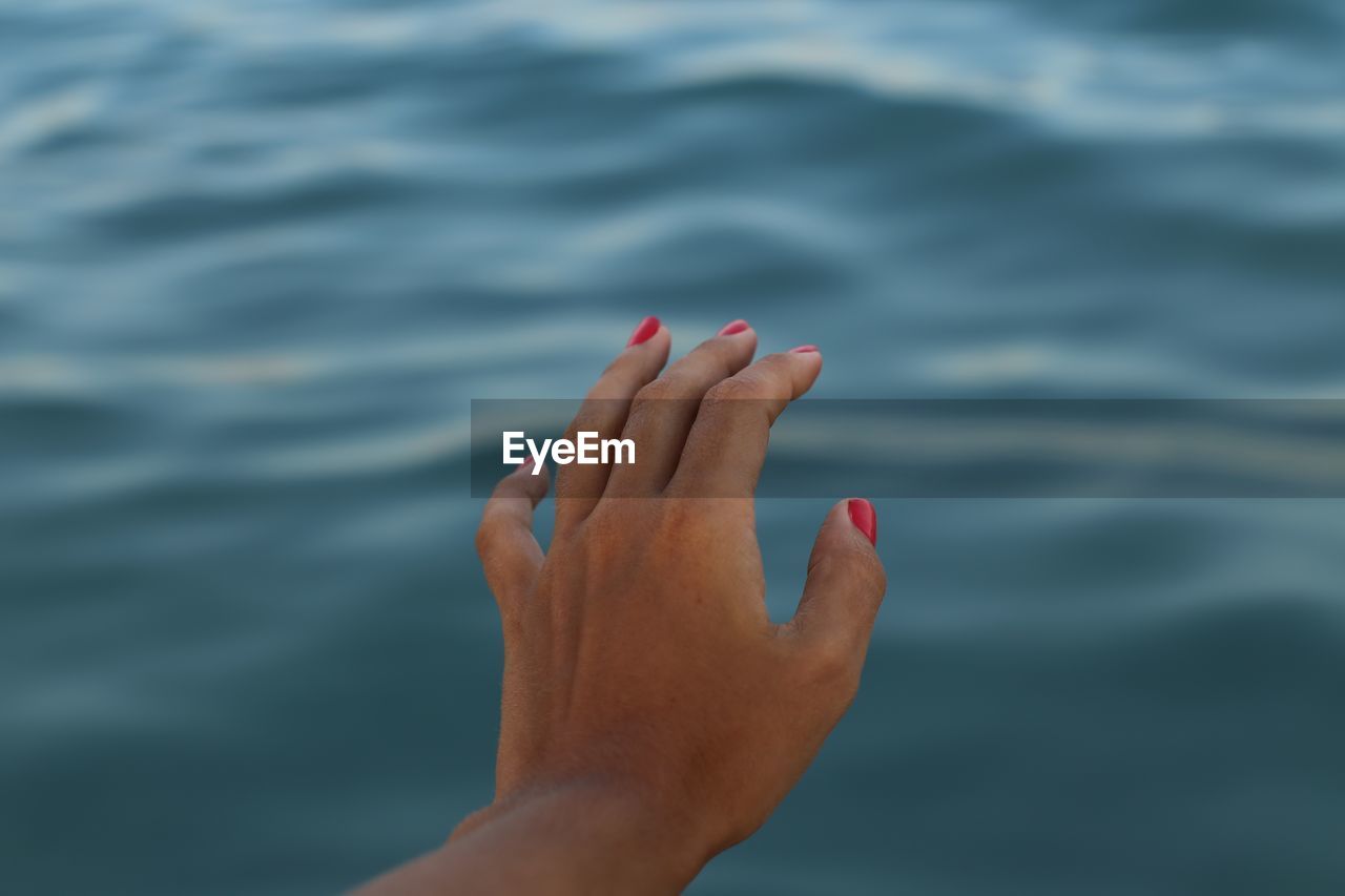 Cropped image of woman hand by sea