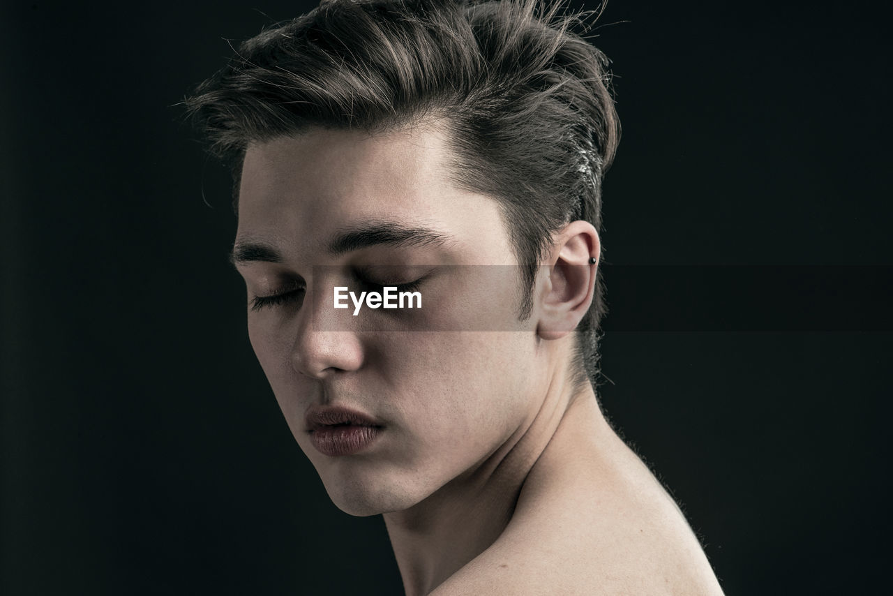 Close-up of young man against black background